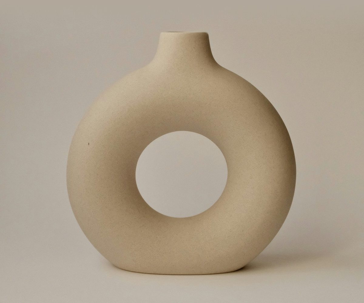 The Halo in sand, a ring-shaped stoneware diffuser on a matching taupe backdrop
