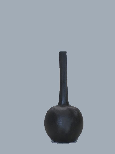 The Halo Bud in slate, a slim black stoneware diffuser against a blue-gray wall