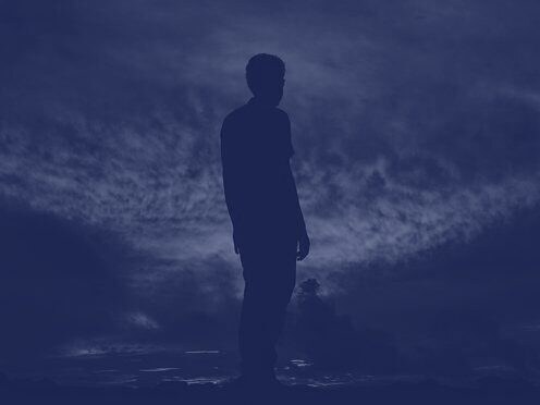 A figure silhouetted against a dark dusk sky