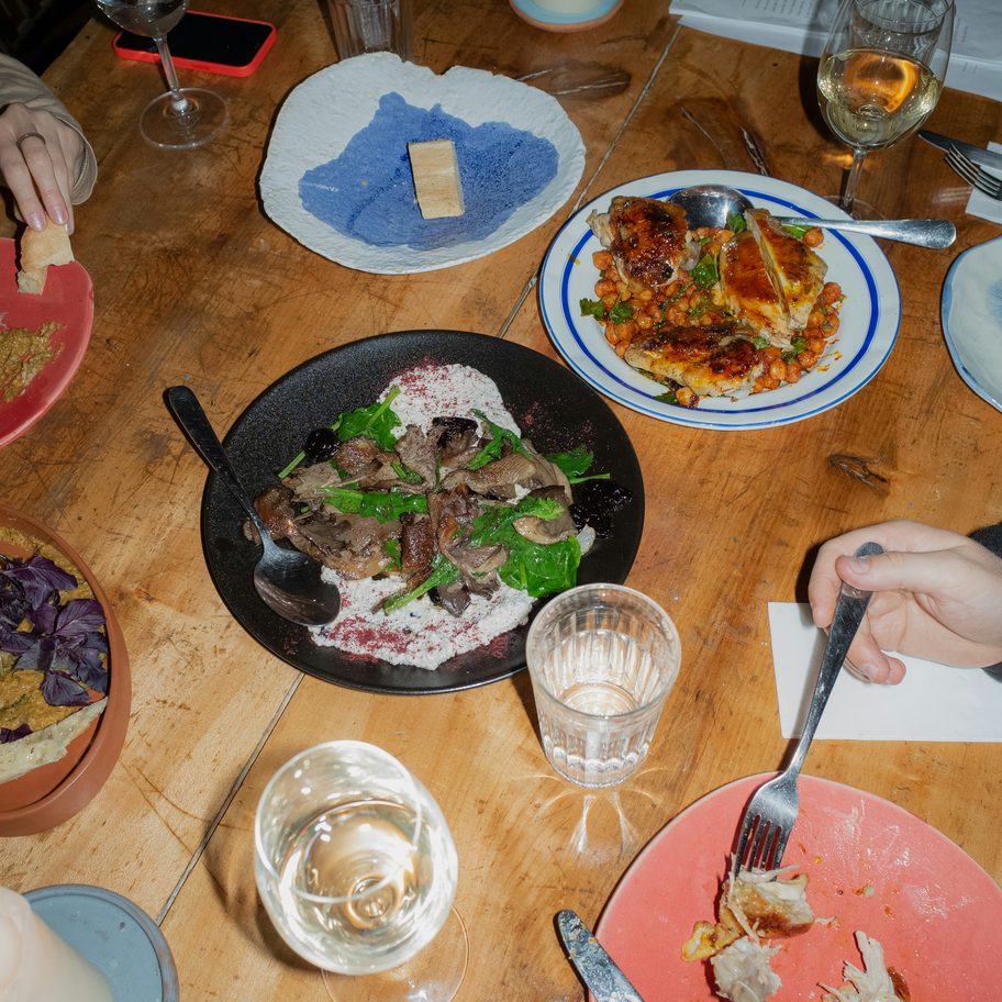 Friends reaching across a crowded table of shared plates