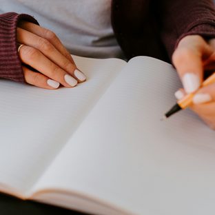 A hand writing in an open paper notebook