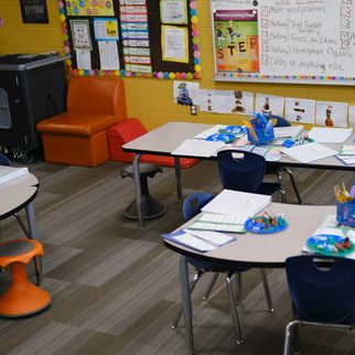 Low tables and blue chairs in a bright, colorful elementary classroom