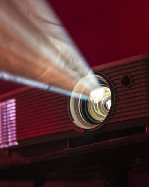 A projector throwing a beam of light across a dark red room