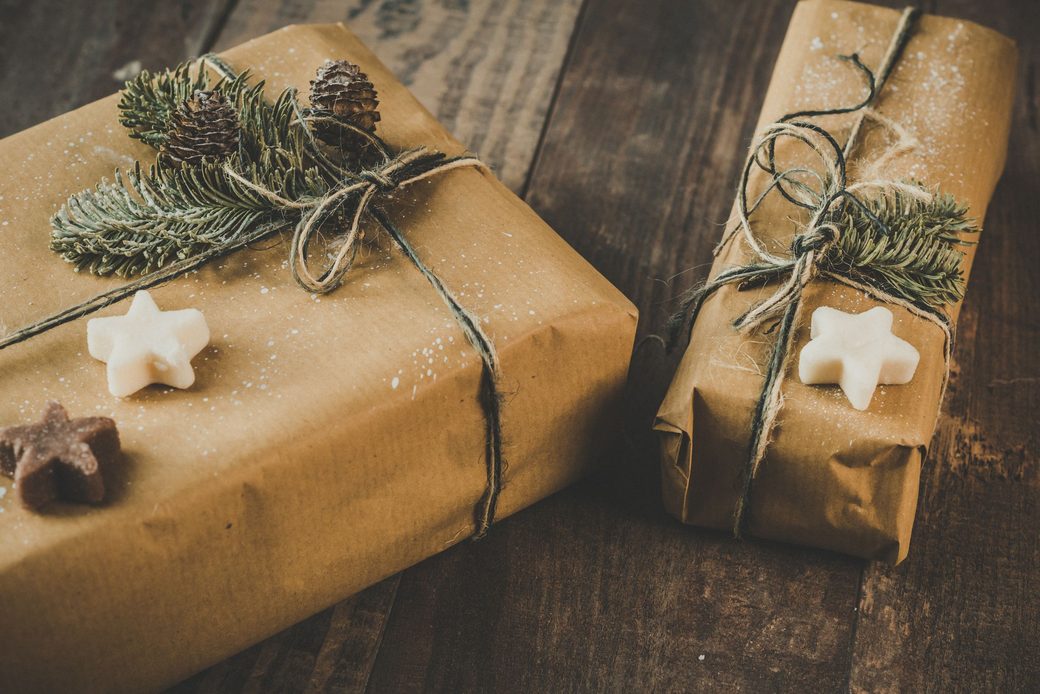 Two gifts wrapped in kraft paper and twine with sprigs of fir on a wooden table