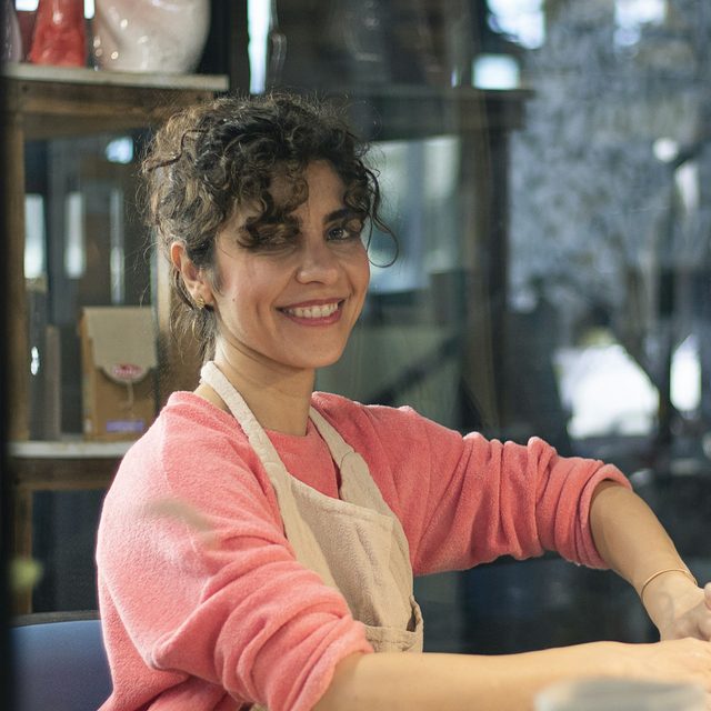Odalys smiling at her worktable in a ceramics studio