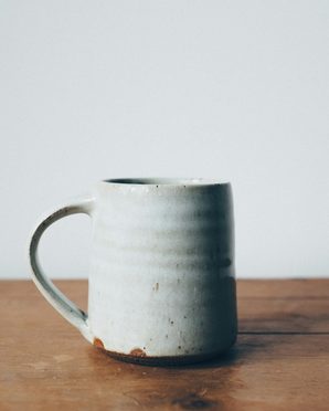 A pale gray glazed mug on a wooden table