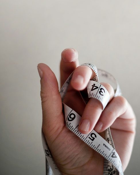 A hand holding a soft tape measure