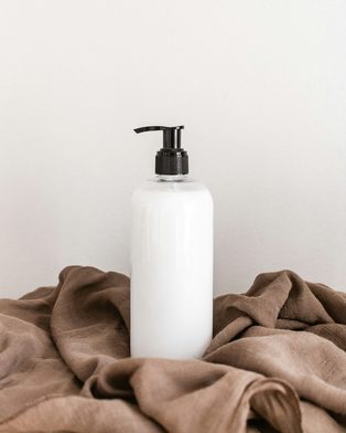 A white pump bottle of cleanser on soft brown linen