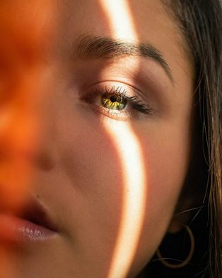 A close-up of a woman's face crossed by a stripe of sunlight