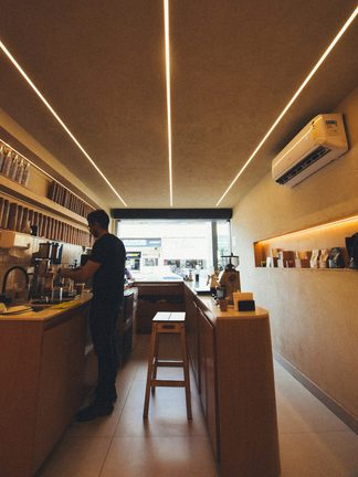 A narrow cafe with a wooden counter and a barista at work