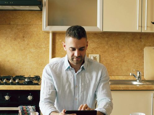 Homeowner reviewing a financing plan on a tablet in his kitchen