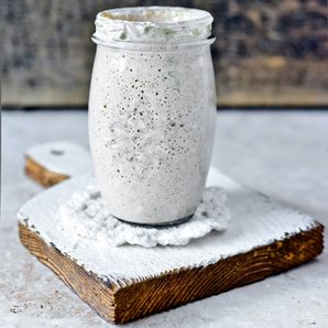 A jar of bubbly sourdough starter on a floured board