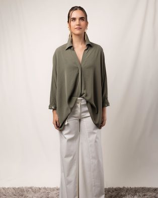 A woman in a sage shirt and cream wide-leg trousers