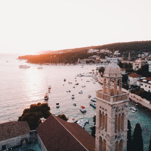 A hillside harbor town with boats in the bay at golden hour