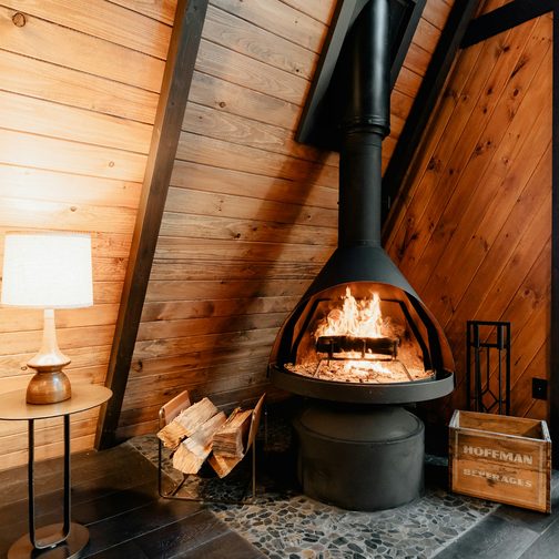 An A-frame cabin interior with a black wood stove