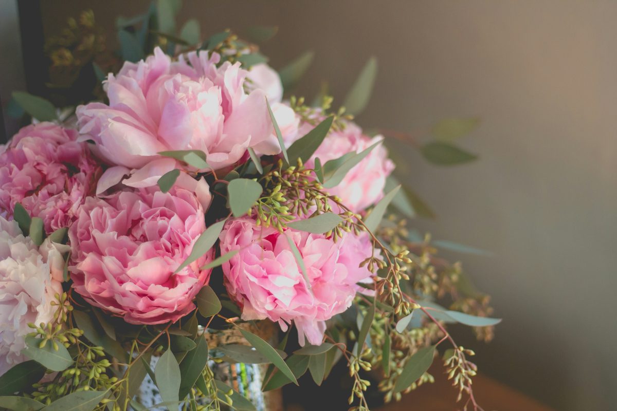 A loose bouquet of pink peonies and eucalyptus on a wooden table