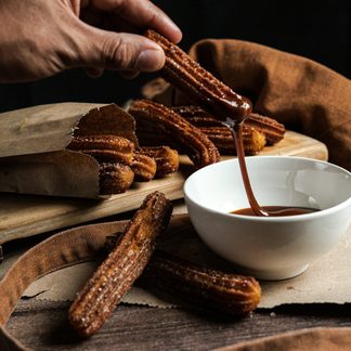 Churros being dipped in chocolate