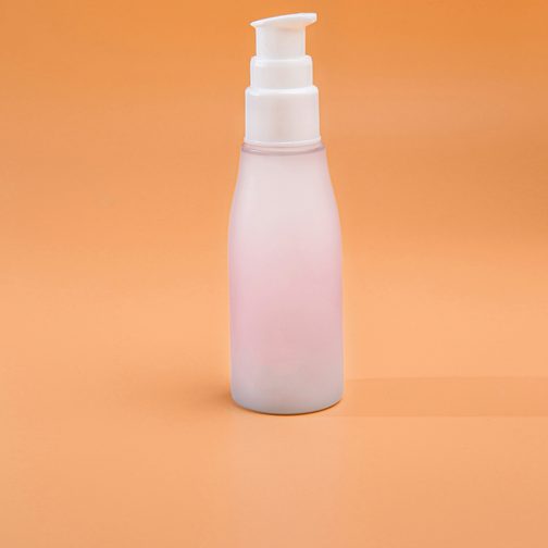 A blank white pump bottle standing on a bright orange backdrop