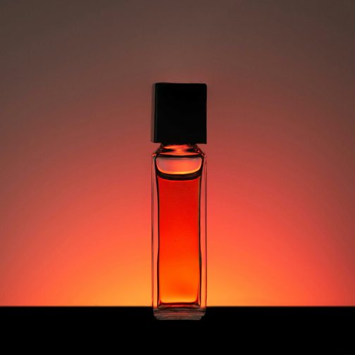 A glass bottle of amber liquid lit from behind with a red glow