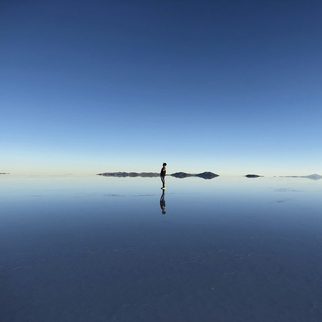 A lone figure reflected on the salt flats at dawn