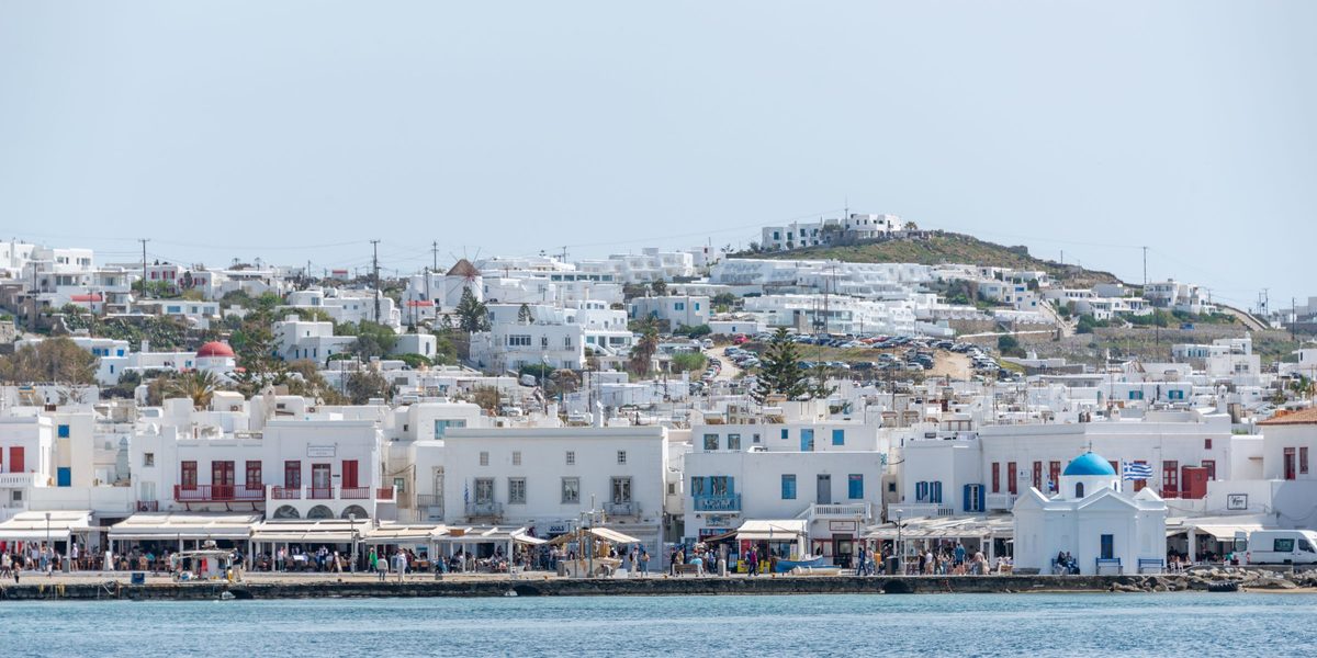 A white seaside town on a hill above a calm blue sea