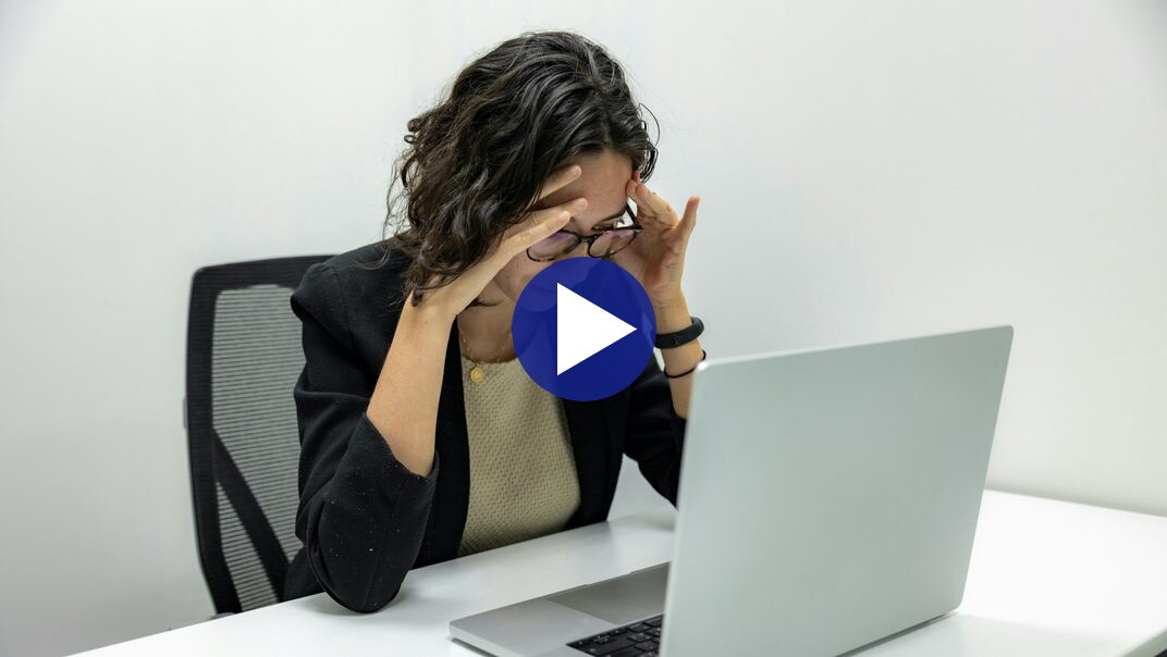 Video still: a person at a desk reacting to a laptop screen