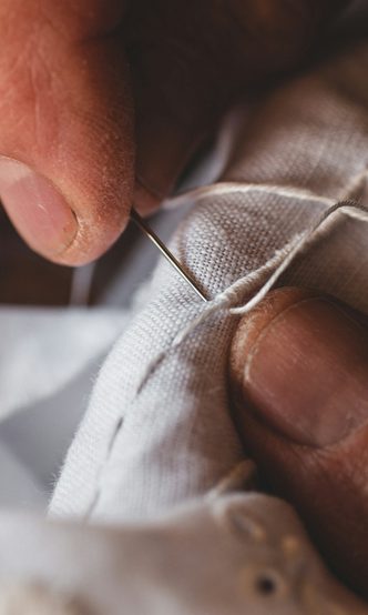 Hands stitching the seam of a white garment
