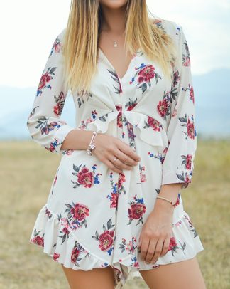 A woman in a white floral romper in a field