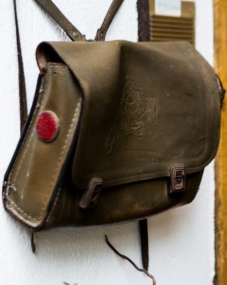 A vintage olive leather satchel hanging on a wall