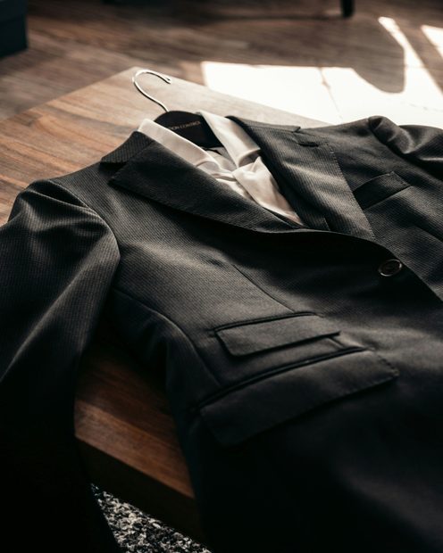 A black wool blazer laid on a dark wooden table