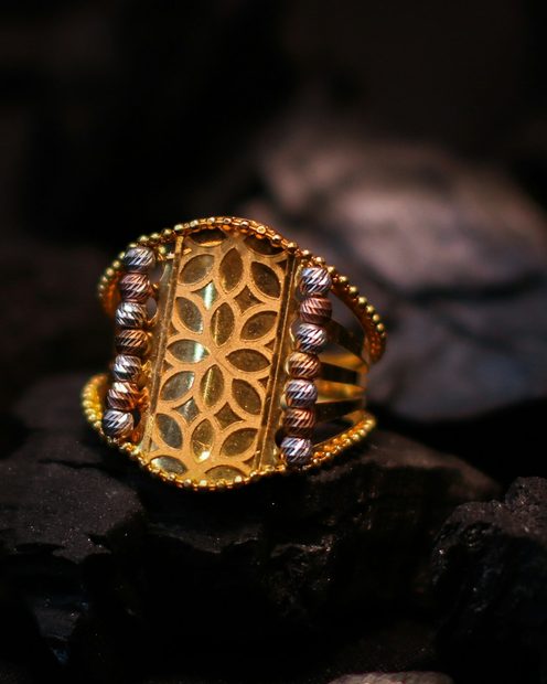 A gold filigree ring resting on dark stone