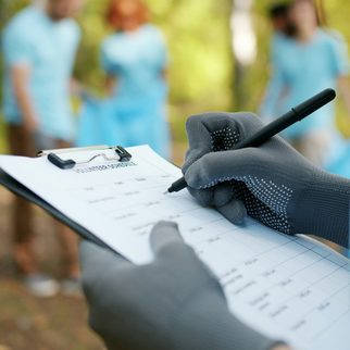 A volunteer in gloves writing on a clipboard