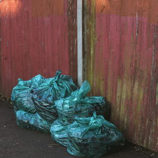 Full trash bags stacked against a painted wall
