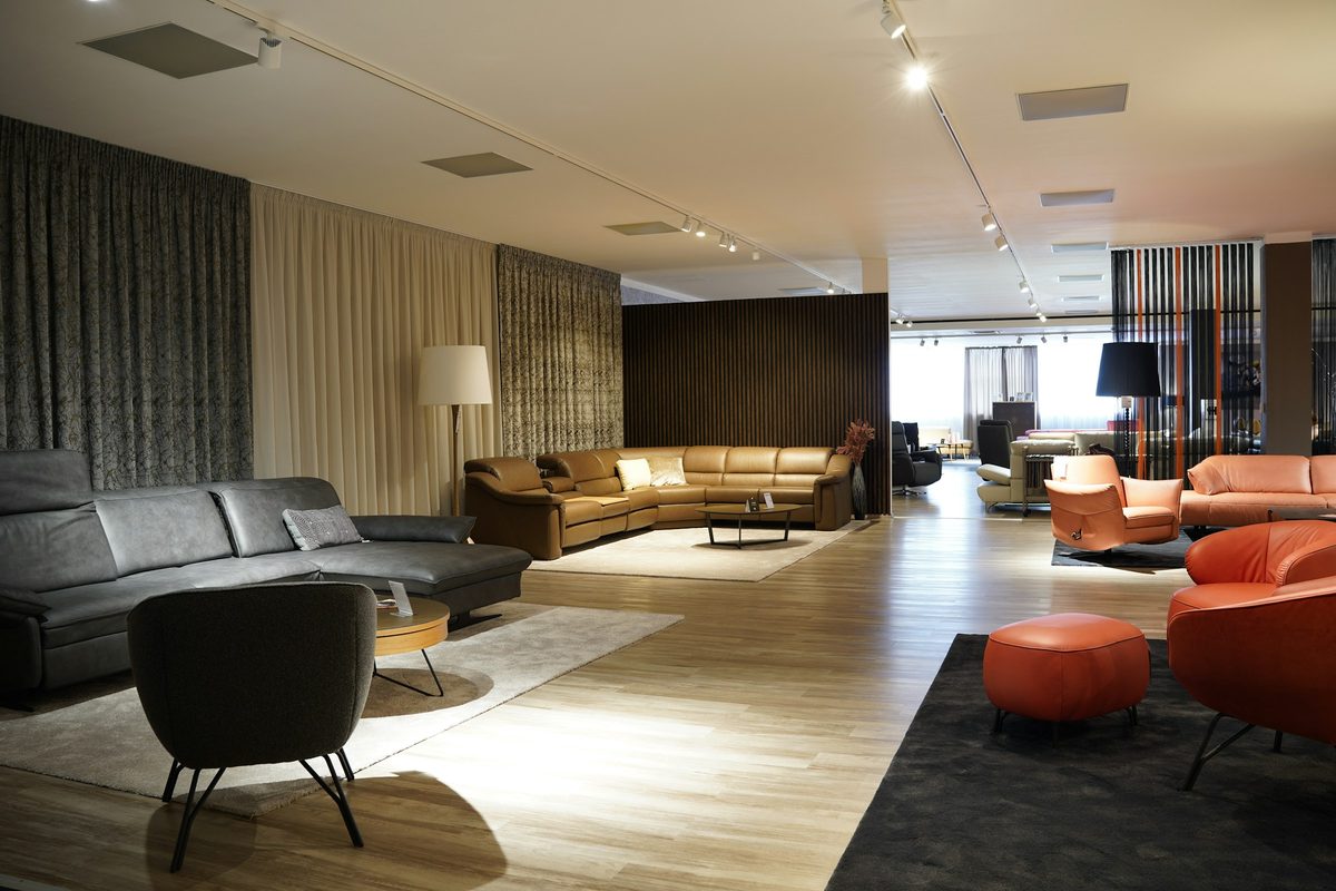 A furniture showroom with sofas and armchairs laid out under track lights