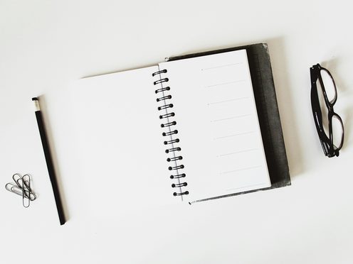 An open spiral notebook with a black pen