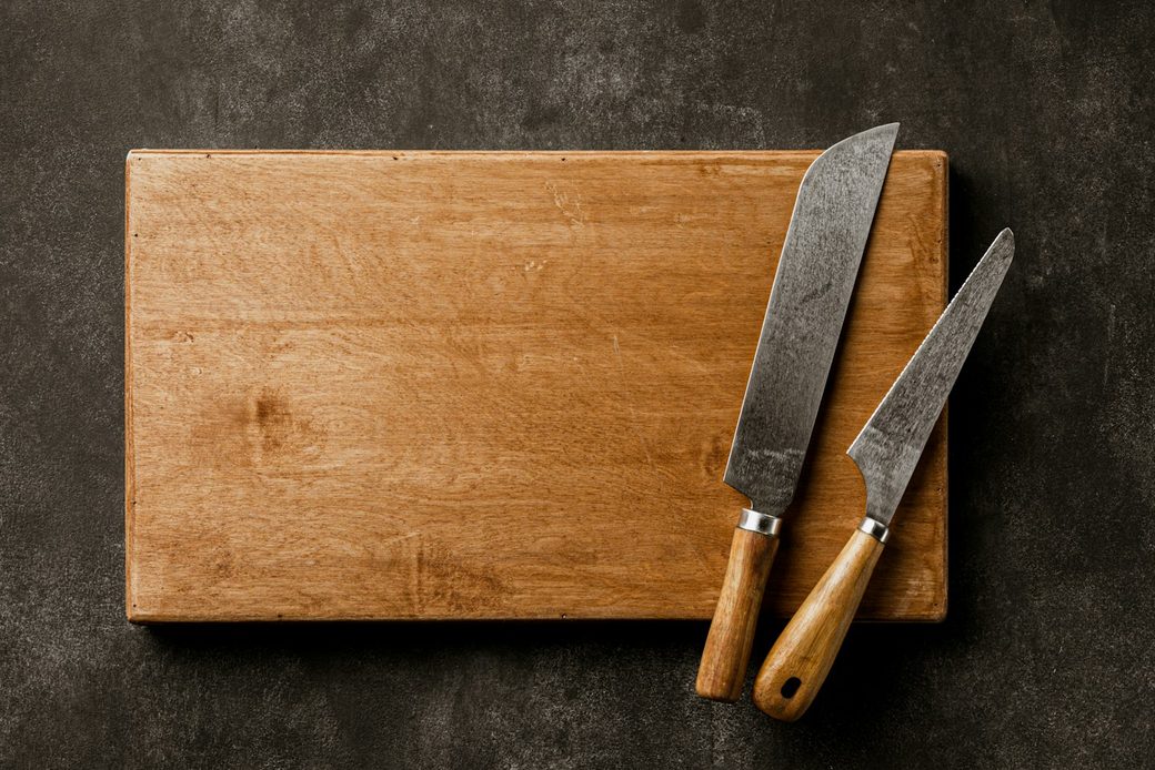 Two hand-forged knives with wooden handles on an oak board