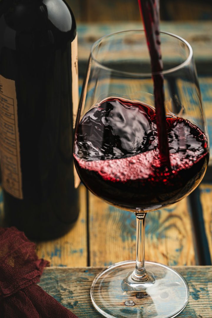 Red wine being poured into a glass on a wooden table